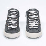 Front view of mid top khaki sneaker. Full suede upper with studs, an internal zip and vintage rubber sole.