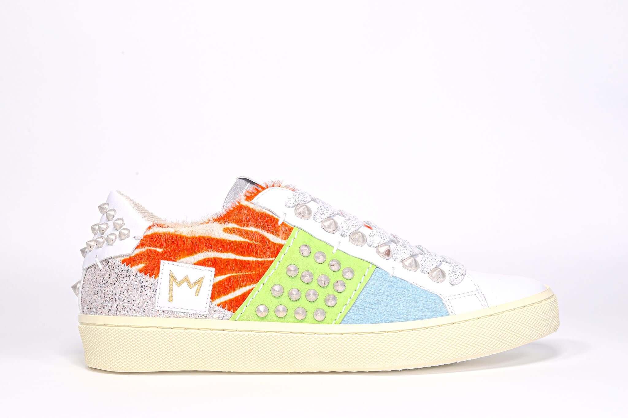 Side profile of low top sneaker. Patchwork upper of mixed materials and silver studs.