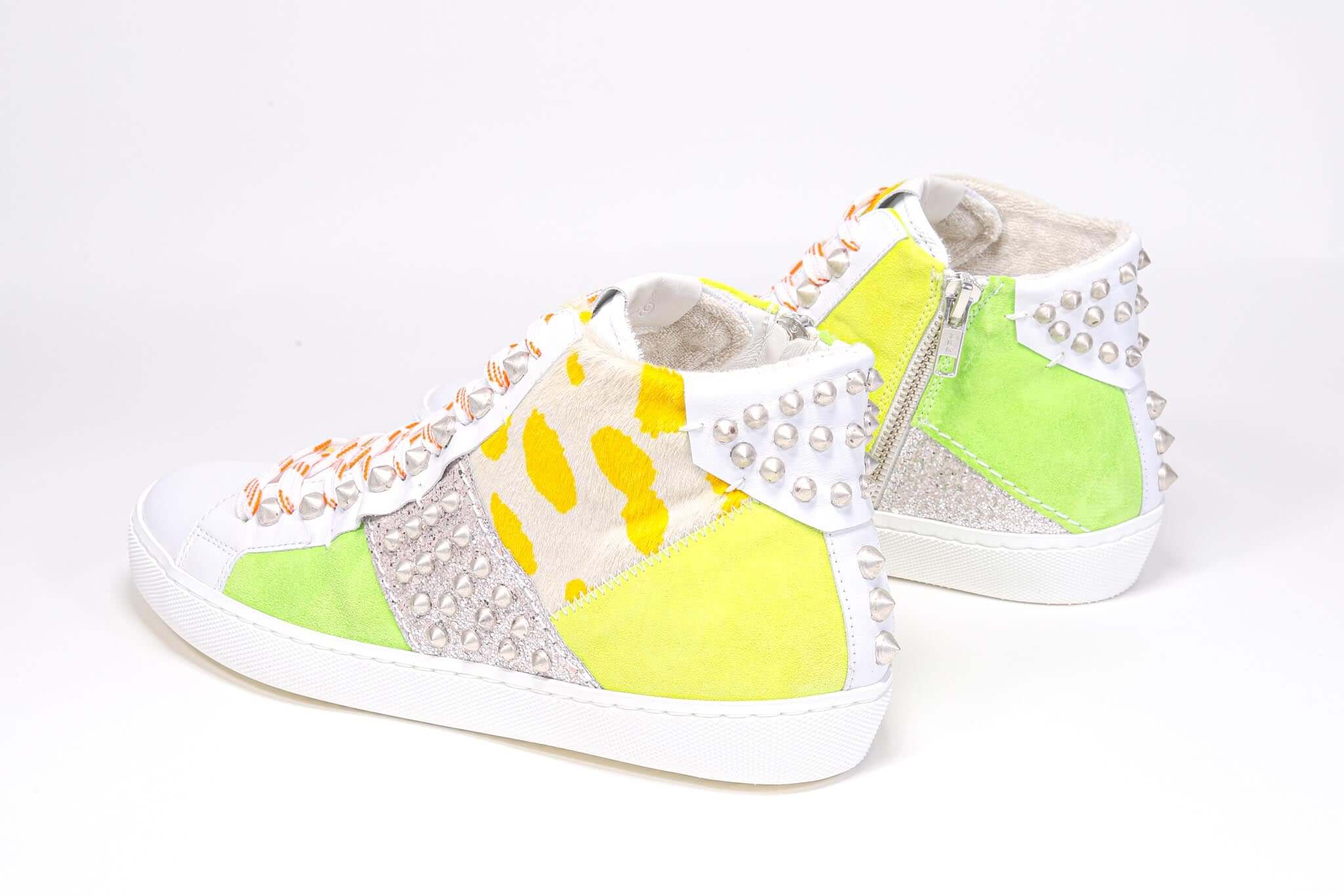Vue de trois quarts arrière de la partie médiane de la chaussure sneaker. Tige en patchwork de matériaux mixtes et clous argentés.