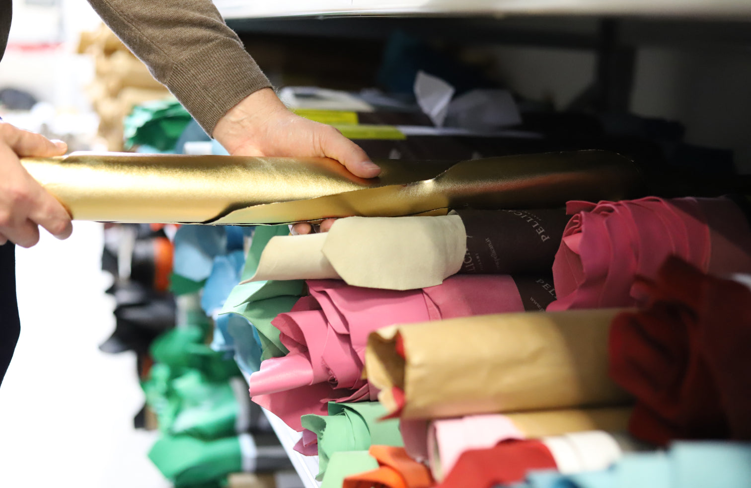 Selecting colourful leathers from a shelf of leathers. 