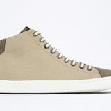 Side profile of mid top sneaker with full beige canvas upper, internal zip and white sole.