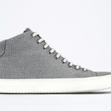 Side profile of mid top sneaker with full grey canvas upper, internal zip and white sole.