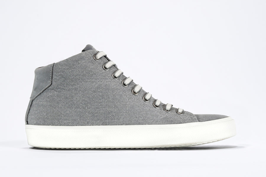 Side profile of mid top sneaker with full grey canvas upper, internal zip and white sole.
