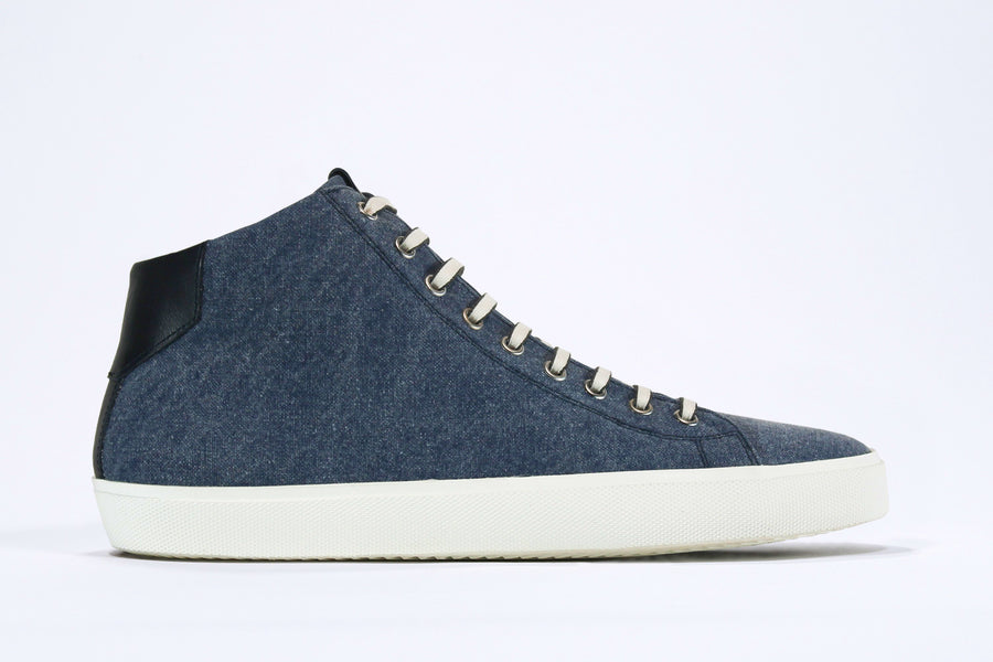  Side profile of mid top sneaker in denim blue canvas and leather upper, internal zip and white sole.