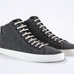 Three quarter front view of mid top sneaker in black canvas and leather upper, internal zip and white sole.