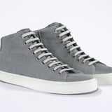 Three quarter front view of mid top sneaker with full grey canvas upper, internal zip and white sole.