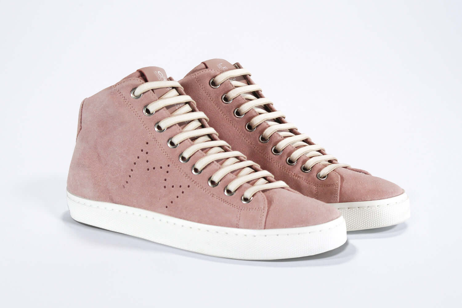 Three quarter front view of mid top sneaker in pink suede and leather upper, internal zip and white sole.