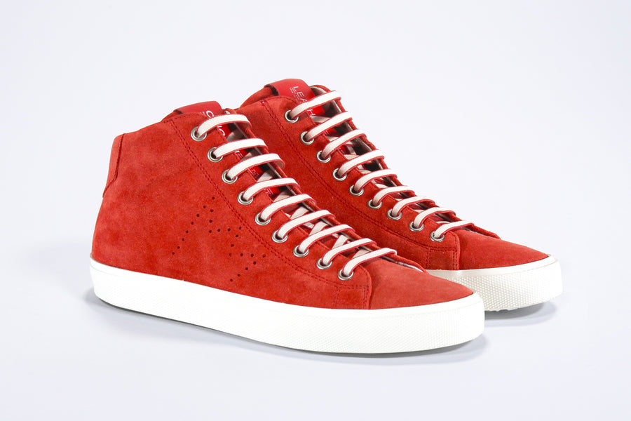 Three quarter front view of mid top sneaker in red suede and leather upper, internal zip and white sole.