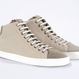 Three quarter front view of mid top sneaker with full beige canvas upper, internal zip and white sole.