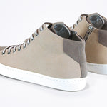 Three quarter back view of mid top sneaker with full beige canvas upper, internal zip and white sole.