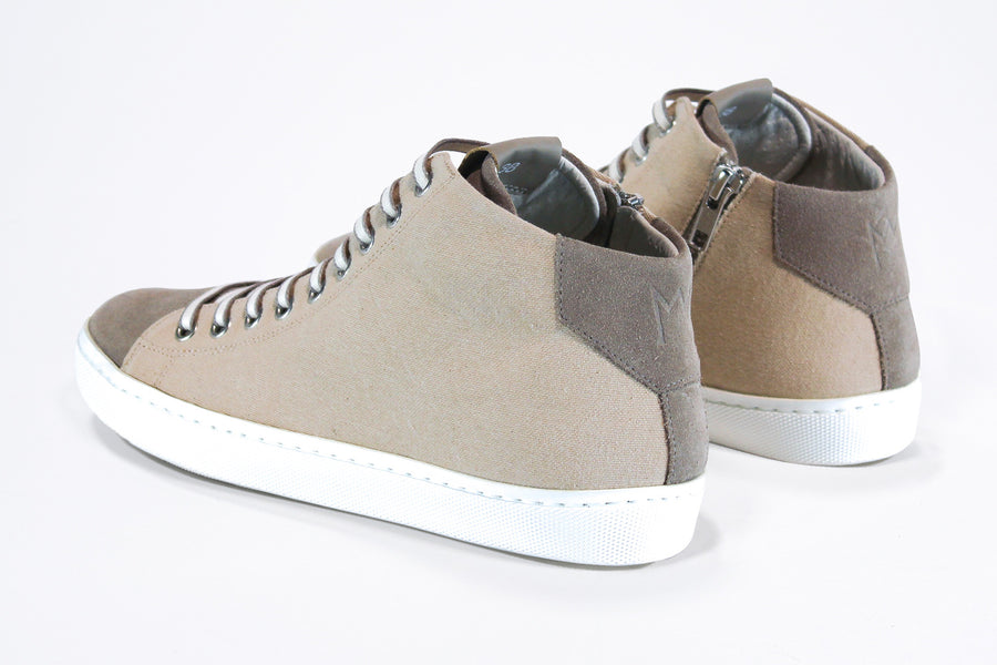 Three quarter back view of mid top sneaker with full beige canvas upper, internal zip and white sole.