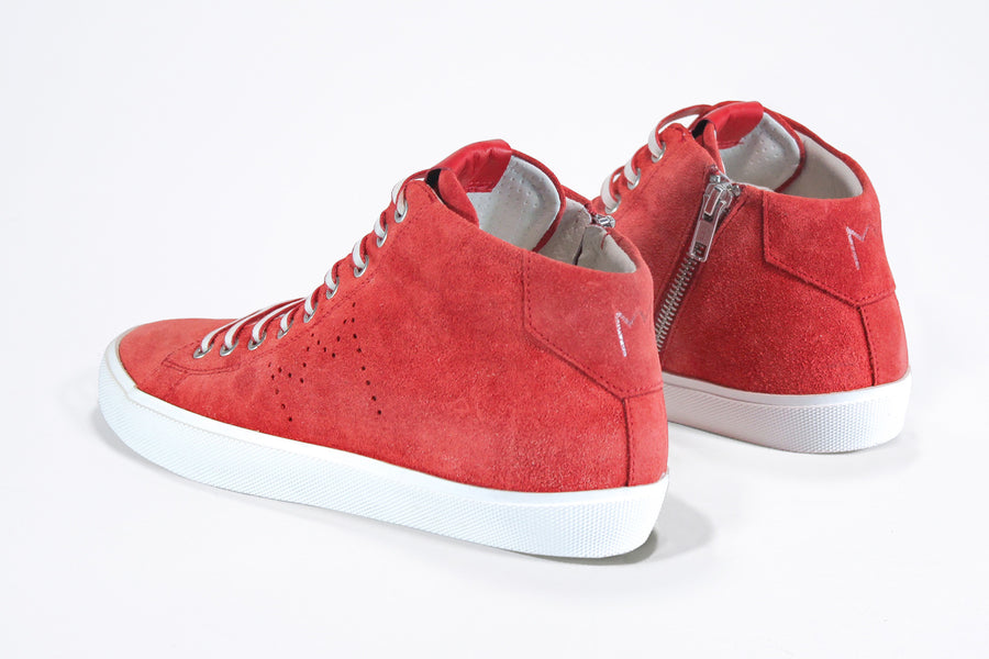  Three quarter back view of mid top sneaker in red suede and leather upper, internal zip and white sole.