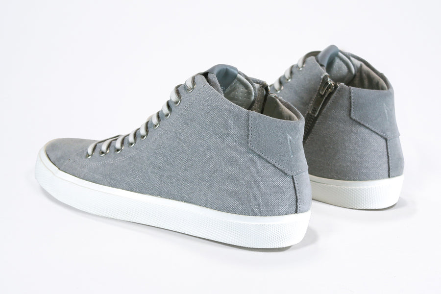 Three quarter back view of mid top sneaker with full grey canvas upper, internal zip and white sole.