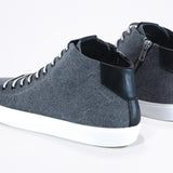 Three quarter back view of mid top sneaker in black canvas and leather upper, internal zip and white sole.