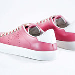  Three quarter back view of low top pink sneaker with white detailing and perforated crown logo on upper. Full leather upper and white rubber sole.