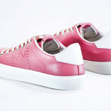  Three quarter back view of low top pink sneaker with white detailing and perforated crown logo on upper. Full leather upper and white rubber sole.