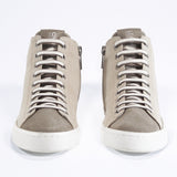 Front view of mid top sneaker with full beige canvas upper, internal zip and white sole.