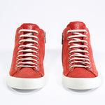 Front view of mid top sneaker in red suede and leather upper, internal zip and white sole.