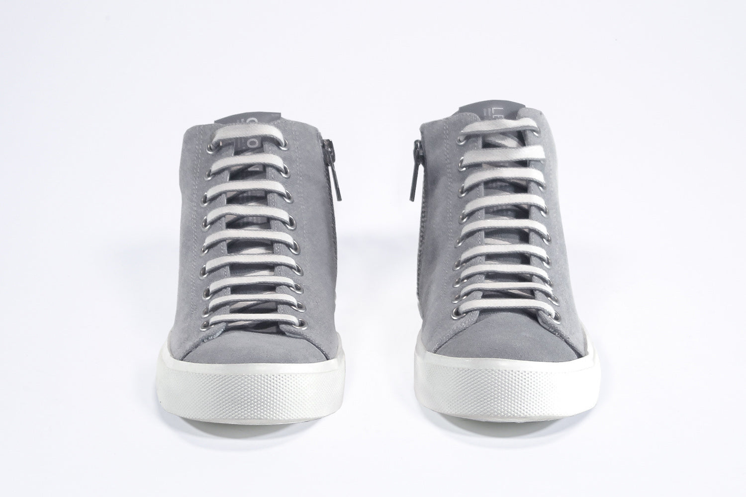 Vista frontale del modello mid top sneaker con tomaia in tela grigia, zip interna e suola bianca.