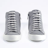 Vue de face du modèle mid top sneaker avec une tige en toile grise, une fermeture éclair interne et une semelle blanche.