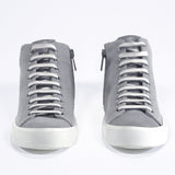 Vista frontale del modello mid top sneaker con tomaia in tela grigia, zip interna e suola bianca.