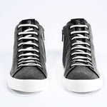 Front view of mid top sneaker in black canvas and leather upper, internal zip and white sole.