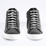 Front view of mid top sneaker in black canvas and leather upper, internal zip and white sole.