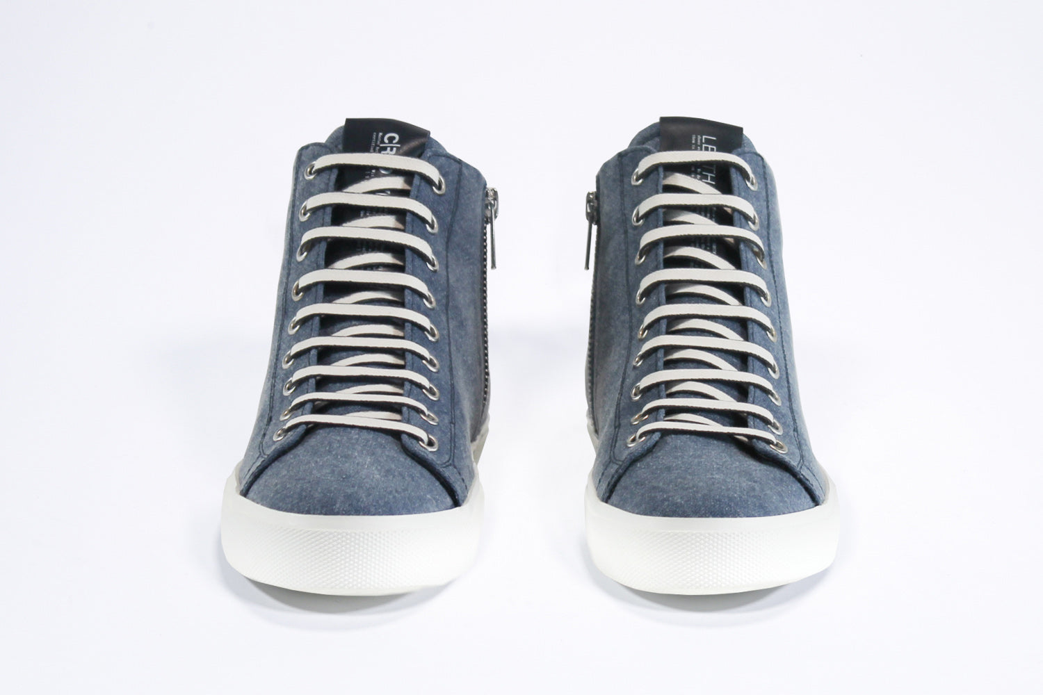 Vorderansicht des Mid-Tops sneaker aus jeansblauem Canvas und Leder, mit Innenreißverschluss und weißer Sohle.