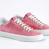  Three quarter front view of low top pink sneaker with white detailing and perforated crown logo on upper. Full leather upper and white rubber sole.