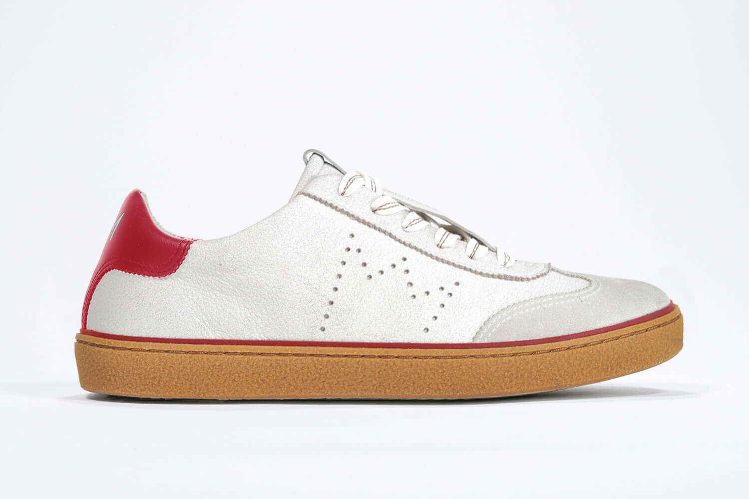 Side view of low top retro sneaker in distressed white leather with red detailing and honey coloured recycled rubber sole.