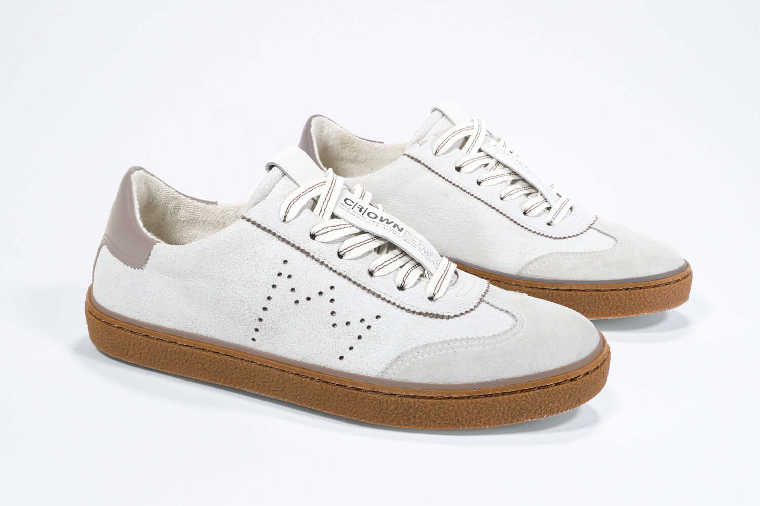 Three quarter front view of low top retro sneaker in distressed white leather with fawn detailing and honey coloured recycled rubber sole.