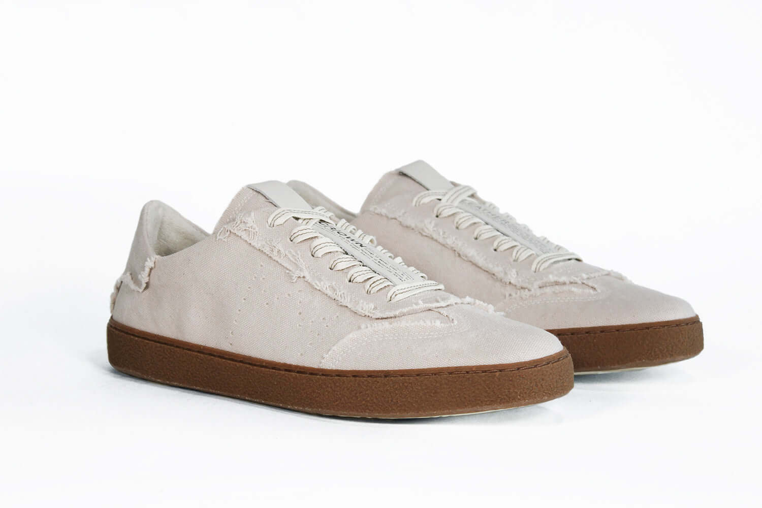 Three quarter front view of low top retro sneaker in distressed stone canvas, with honey coloured recycled rubber sole.