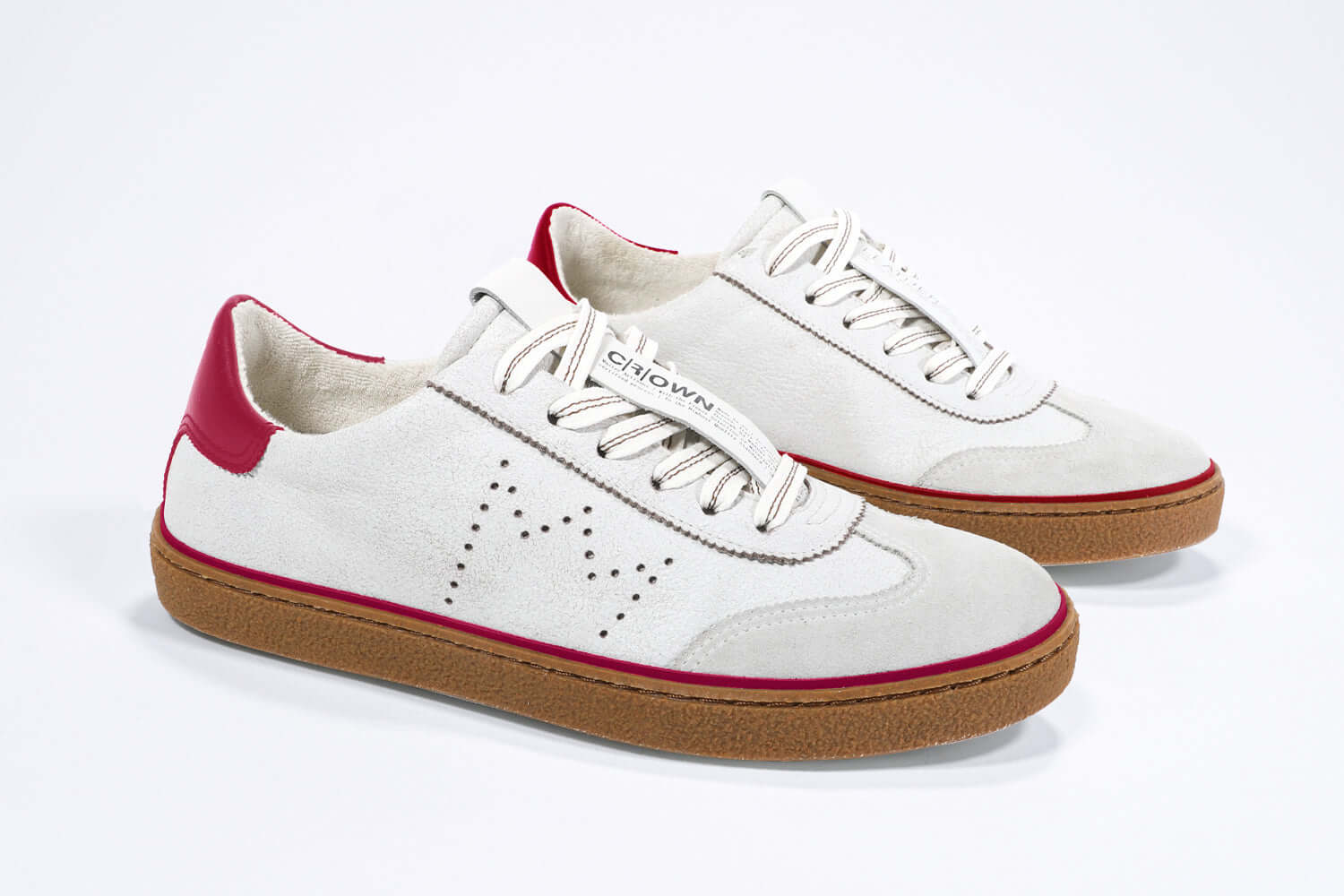 Three quarter front view of low top retro sneaker in distressed white leather with red detailing and honey coloured recycled rubber sole.
