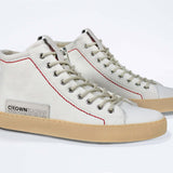 Three quarter front view of high top canvas sneaker. Canvas white upper with signature red stitching and a pale natural rubber sole.
