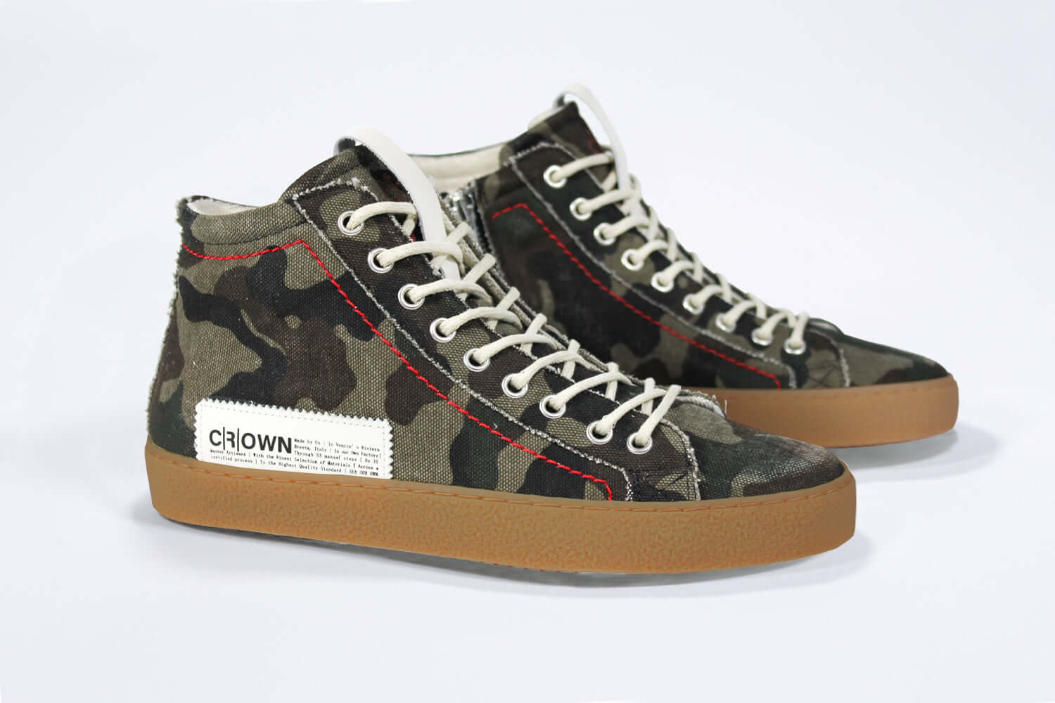 Three quarter front view of high top canvas sneaker. Camouflage canvas upper with signature red stitching and a dark natural rubber sole.