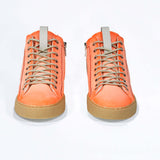 Front view of high top canvas sneaker. Canvas upper hand painted in gradated fluo orange paint. Pale natural rubber sole.