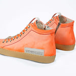 Back view of high top canvas sneaker. Canvas upper hand painted in gradated fluo orange paint. Pale natural rubber sole.