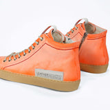 Back view of high top canvas sneaker. Canvas upper hand painted in gradated fluo orange paint. Pale natural rubber sole.