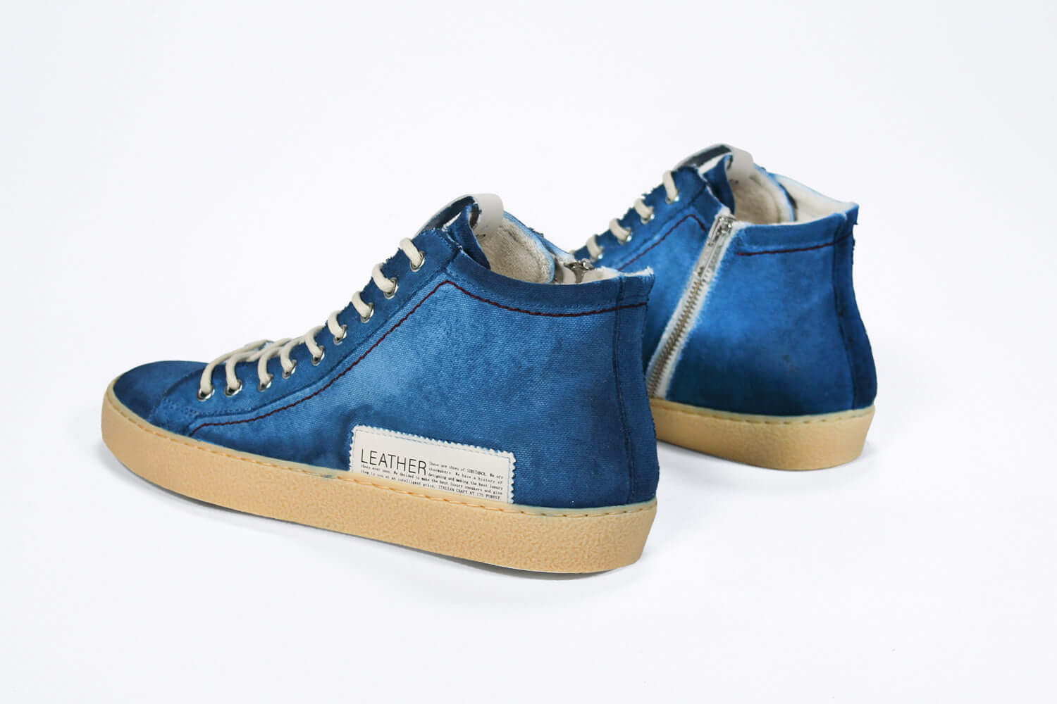 Back view of high top canvas sneaker. Canvas upper hand painted in gradated blue paint. Pale natural rubber sole.