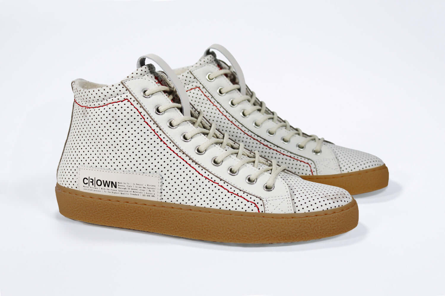 Three quarter front view of high top perforated aged white leather sneaker with signature red stitching and a dark natural rubber sole.