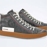 Three quarter front view of high top perforated aged black leather sneaker with signature red stitching and a dark natural rubber sole.