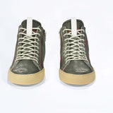 Front view of high top perforated aged khaki leather sneaker with signature red stitching and a pale natural rubber sole.