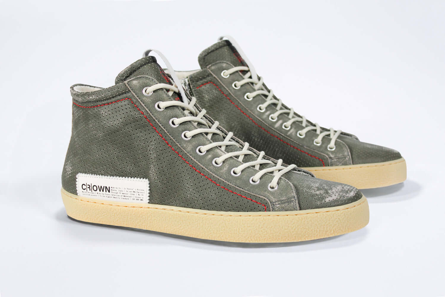 Three quarter front view of high top perforated aged khaki leather sneaker with signature red stitching and a pale natural rubber sole.
