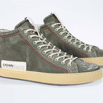 Three quarter front view of high top perforated aged khaki leather sneaker with signature red stitching and a pale natural rubber sole.