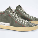 Three quarter front view of high top perforated aged khaki leather sneaker with signature red stitching and a pale natural rubber sole.