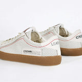 Back view of low top white sneaker. Perforated aged white leather upper with red stitching and dark rubber sole.