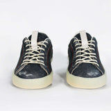 Front view of low top aged navy sneaker with white accents. Perforated navy leather upper with red stitching and pale rubber sole.