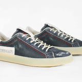 Three quarter front view of low top aged navy sneaker with white accents. Perforated navy leather upper with red stitching and pale rubber sole.