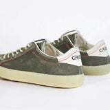 Back view of low top aged khaki sneaker with white accents. Perforated khaki leather upper with red stitching and pale rubber sole.