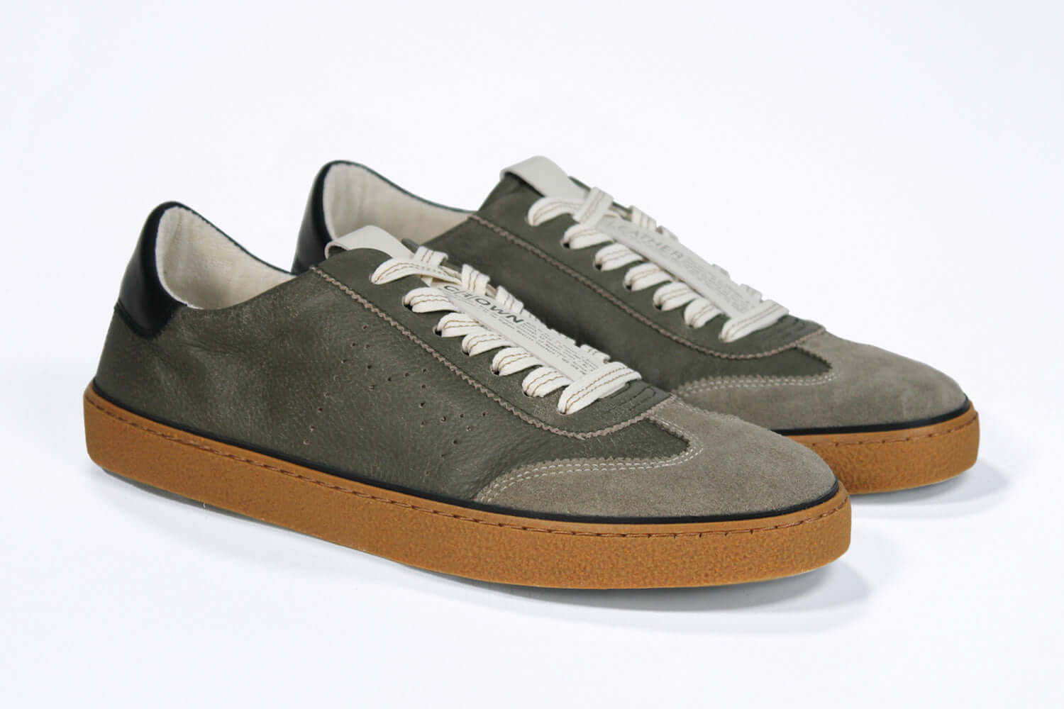 Three quarter front view of low top retro sneaker in distressed khaki leather with black detailing. Set on a honey coloured recycled rubber sole.